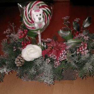 Centre de table floral de Noël dans les tons rouge, rose, vert et blanc, dans un contenant en écorce