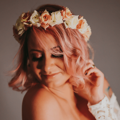 Femme aux cheveux rose cendré portant une couronne de fleurs blanche et rose