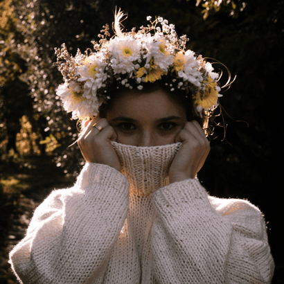 Jeune femme portant un pull blanc et une couronne de fleurs blanche et jaune