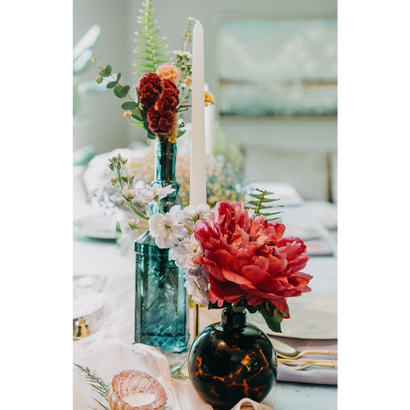 Petits bouquets de fleurs dans une fiole ronde et une bouteille, sur une table de mariage