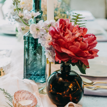 Petits bouquets de fleurs dans une fiole ronde et une bouteille, sur une table de mariage