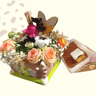 Composition florale réalisée dans une boîte à sucre en forme de maison en pain d'épices