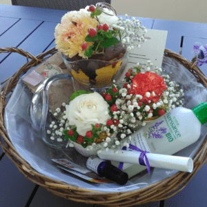 Panier contenant de petites compositions florales dans les tons rouge, jaune et blanc, un sachet de fleurs comestibles, un poème, et des produits de beauté à base de fleurs