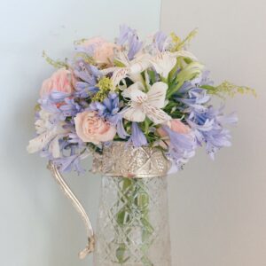 Bouquet de fleurs mauves, rose pâle et blanches dans un vase carafe