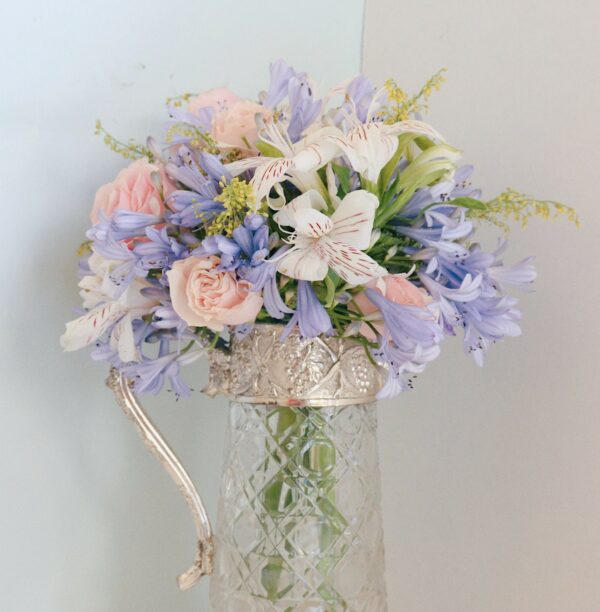 Bouquet de fleurs mauves, rose pâle et blanches dans un vase carafe